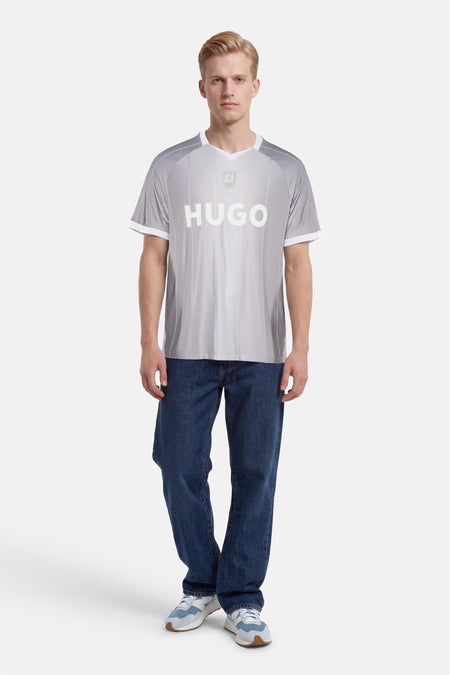 Grijs T-shirt met diagonale strepen van HUGO, met wit logo, embleem, V-hals en witte boorden, gedragen door een man.