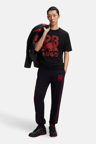 Zwart T-shirt met korte mouwen van HUGO, met een rode print op de voorkant en een model met een leren jas over de schouder.
