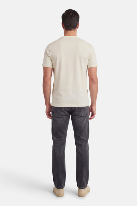 T-shirt écru à manches courtes de HUGO, vue de dos, combiné avec un jean foncé et des chaussures beiges.