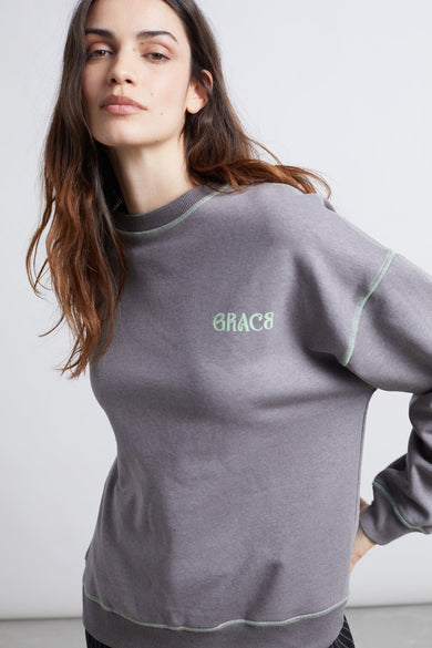 Gilet gris avec col rond de 24 couleurs, avec un point vert clair et le mot "GRACE" brodé.