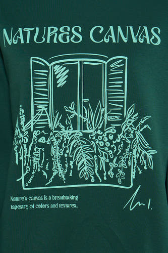 Gilet vert avec col rond de 24 Colleurs GMBH, avec un dessin d'une fenêtre pleine de plantes.