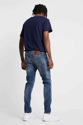 Blauwe slim fit jeans van G-Star RAW, met een licht vervaagde wassing en witte sneakers.