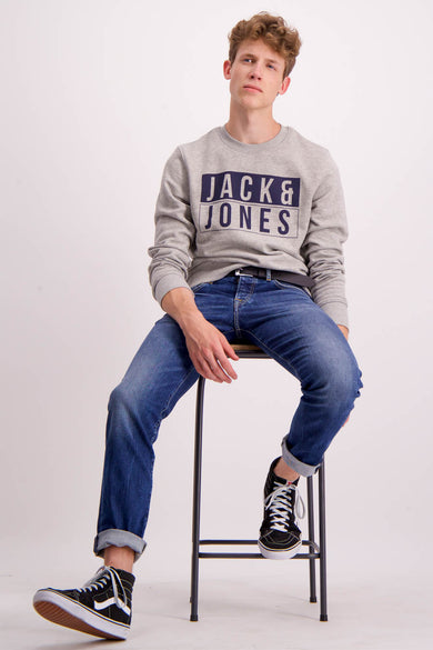 Ceinture noire de Levi's® Accessories, portée avec un pull gris et des jeans bleus, assise sur une chaise roulante.