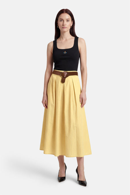 Gele rok van Terra di Siena, met verticale strepen, gecombineerd met een zwarte top en bruine riem.