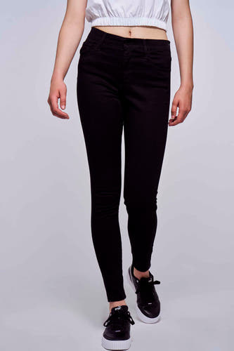 Jean skinny noir de Levi's, vu de l'arrière, associé à une chemise blanche et des baskets noires et blanches.