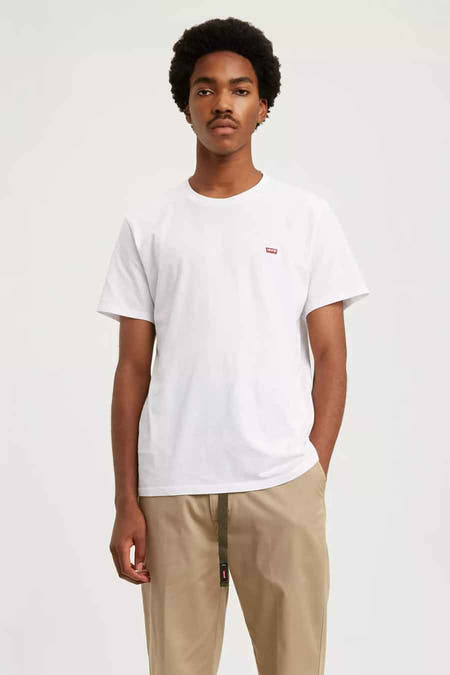 T-shirt blanc de Levi's, à manches courtes et avec un petit logo rouge sur la poitrine, porté avec un pantalon kaki.