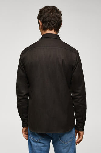 Chemise brune à manches longues de MANGO, vue de derrière, portée avec un jean bleu.