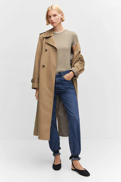 Groene korte mouwen t-shirt van MANGO, gedragen onder een beige trenchcoat, met blauwe jeans en zwarte ballerina’s, front view.