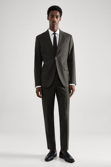 Blazer vert de MANGO, porté avec un chemisier blanc et une cravate noire, avec un pantalon et des chaussures noires.