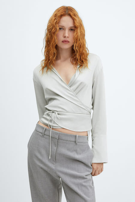 Zilveren hemd met lange mouwen van MANGO, met wikkeldetail en gedragen met grijze pantalon.
