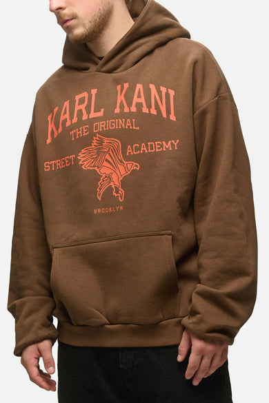 Bruine sweater met kap van Karl Kani, met een oranje logo-opdruk en buidelzak aan de voorkant.
