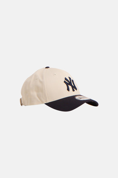 Casquette beige de NEW ERA avec visière bleu foncé et logo sur le devant.