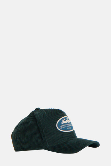 Groene pet van NEW ERA met corduroy textuur en een vintage logo patch aan de voorkant.