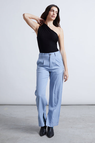 Pantalon bleu de 24 couleurs, avec plis et larges basques fendues, associé à une chemise noire.