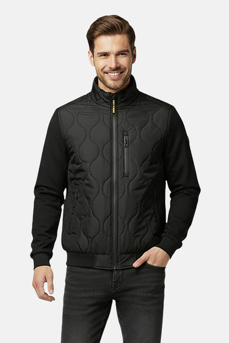 Manteau court et noir de Cars, avec fermeture éclair et motif tricoté sur la devant, associé à des jeans noirs.