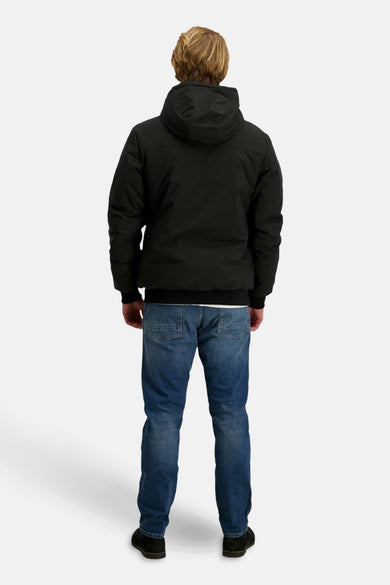 Zwarte korte jas van Cars, met capuchon, gedragen met blauwe jeans en zwarte schoenen, achteraanzicht.

