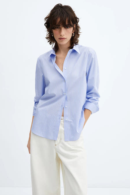 Chemise bleue rayée à manches longues de MANGO, portée avec un pantalon blanc à jambes larges, vue de derrière.