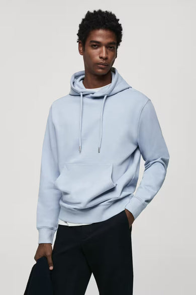 Blauwe sweater met kap van MANGO, met trekkoorden en kangoeroezak, gedragen met zwarte pantalon.