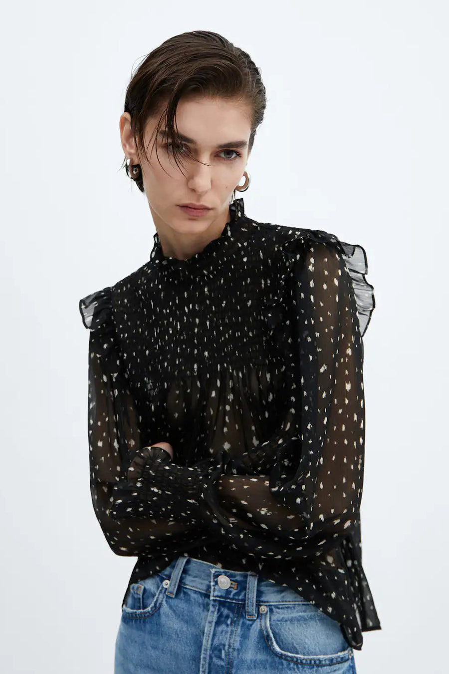 Blouse noire à manches longues de MANGO, avec des rayures et des volants sur les épaules, associée à un jean.