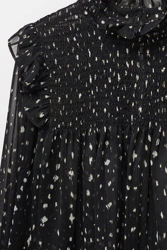Blouse noire de MANGO, avec des manches longues, des détails élastiques et un motif à points.