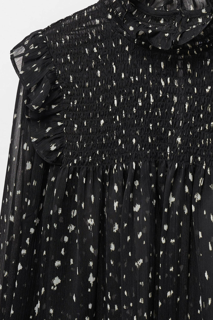 Blouse noire de MANGO, avec des manches longues, des détails élastiques et un motif à points.