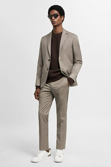 Beige blazer van MANGO, gedragen met een bruine trui en witte sneakers, close-up.
