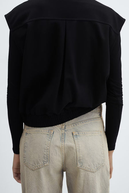 Jean ample en denim de MANGO avec un délavage clair et délavé, vu de dos avec deux poches arrière et un t-shirt noir.