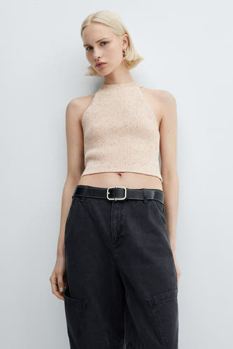 Roze singlet van MANGO, gedragen met een zwarte broek met riem en grote zakken.
