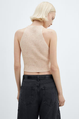 Roze singlet van MANGO, met ribgebreide textuur en een hoge hals, gecombineerd met een zwarte broek met riem.
