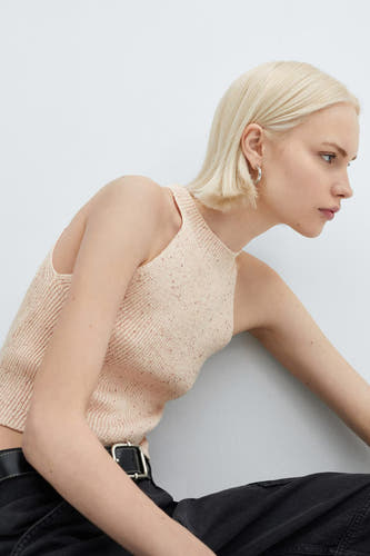 Roze singlet van MANGO, met een ribgebreide textuur, gecombineerd met een zwarte broek en riem.
