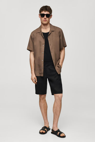 Short noir de MANGO, associé à une chemise brune et des sandales noires.