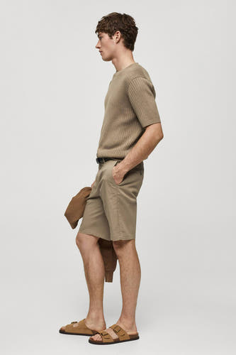 Bruine short van MANGO, met een riem en een bijpassende jas in de hand, gezien in zijaanzicht.
