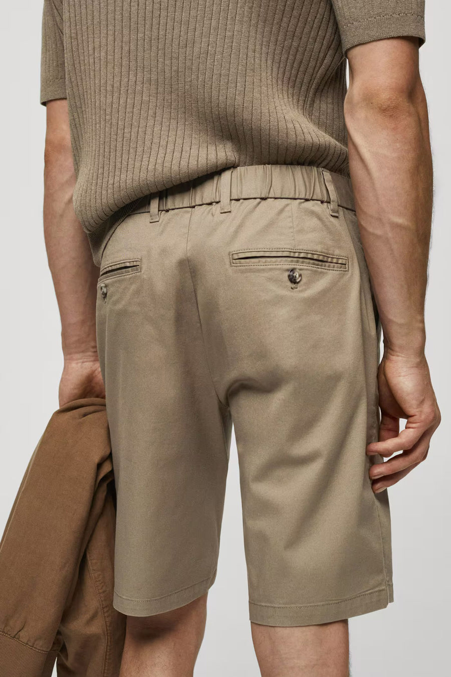 Bruine short van MANGO, met elastische tailleband en zakken aan de achterkant, vastgehouden jas aan de zijkant, achteraanzicht.
