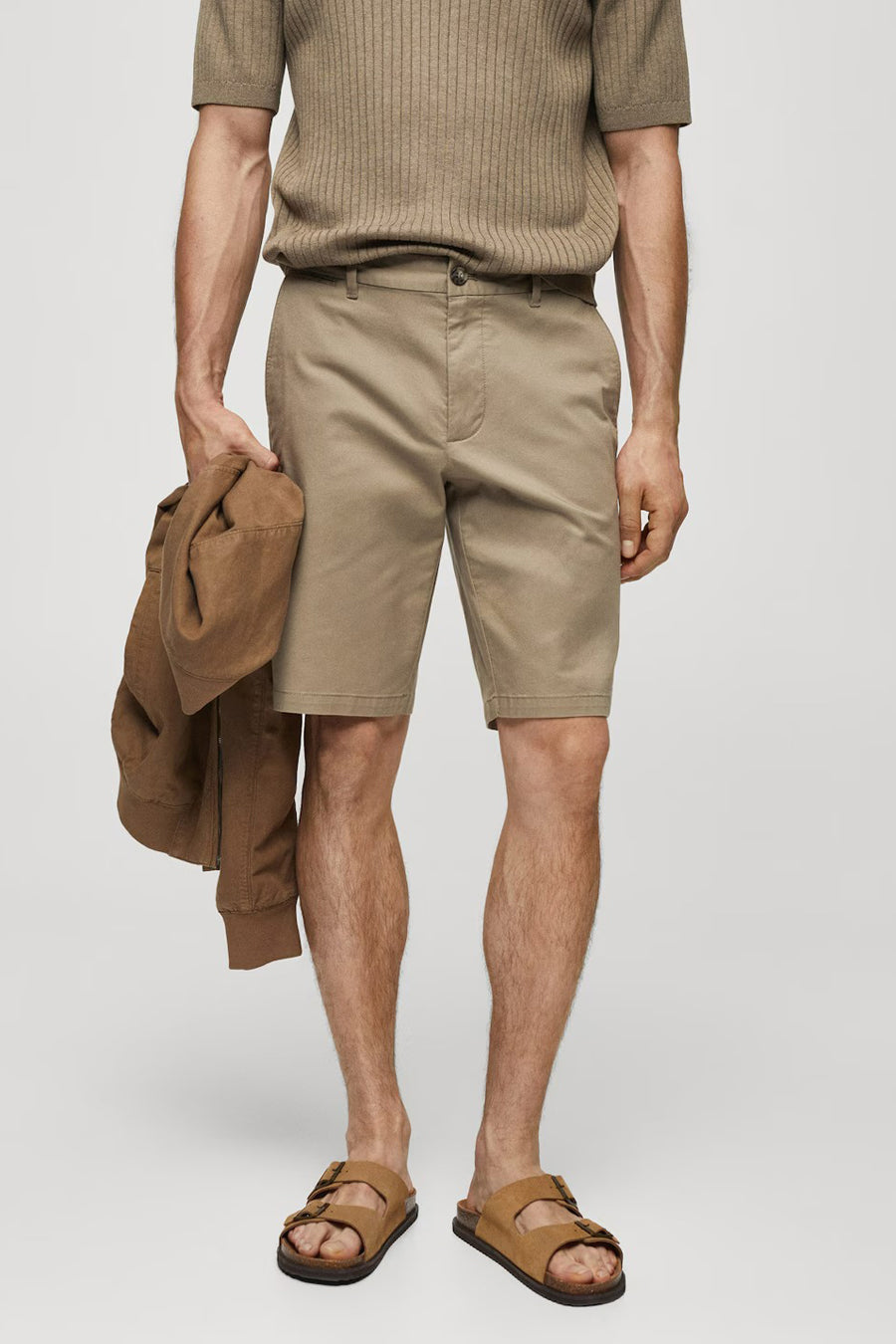 Bruine short van MANGO, gedragen met bruine sandaalen en een bruin shirt, met een bruin jas in de hand.