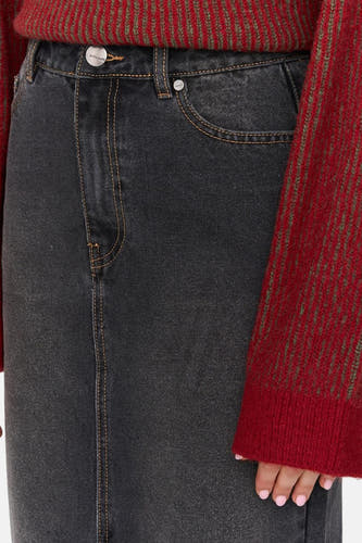 Donkergrijze denim lange rok van 24 colours met gele stiksels, gedragen met een gebreide trui.
