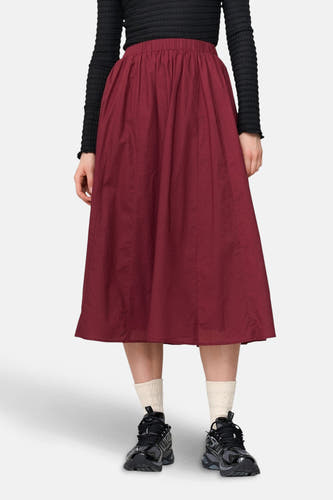 Bordeaux rok van 24 colours gmbh, gecombineerd met een zwart shirt met lange mouwen, witte sokken en zwarte schoenen.