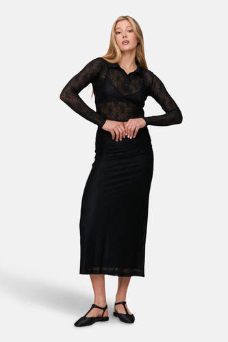 Zwarte rok van 24 colours gmbh, met een doorschijnend geometrisch patroon, gecombineerd met een doorschijnende zwarte blouse en zwarte schoenen.
