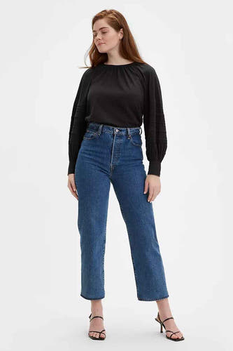Rechte jeans in middenblauw denim van Levi's, gecombineerd met een zwarte blouse en hakken.