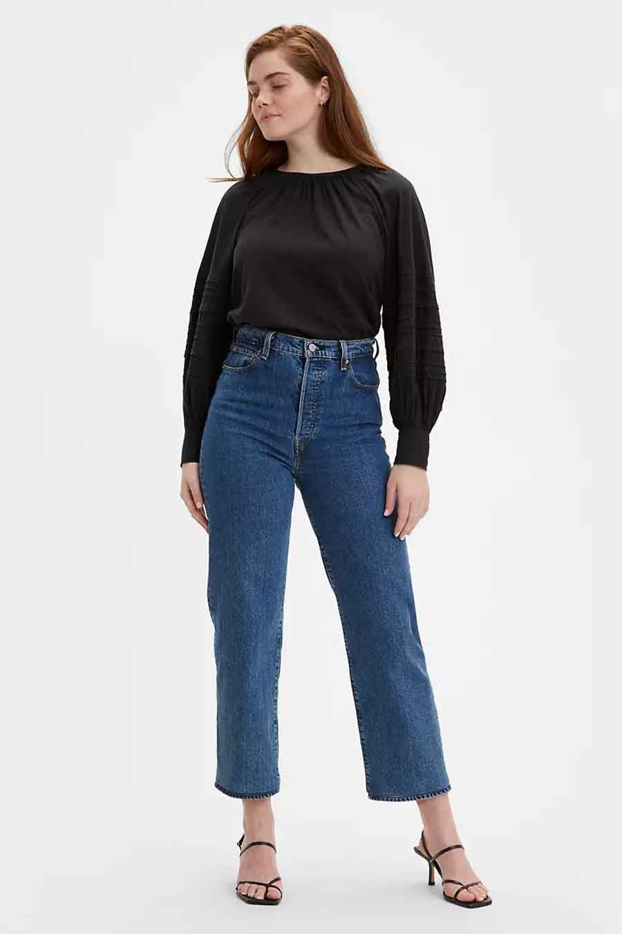 Rechte jeans in middenblauw denim van Levi's, gecombineerd met een zwarte blouse en hakken.