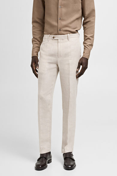 Beige kostuumbroek van MANGO, met een gladde textuur, gecombineerd met een bruin shirt en donkerbruine schoenen.