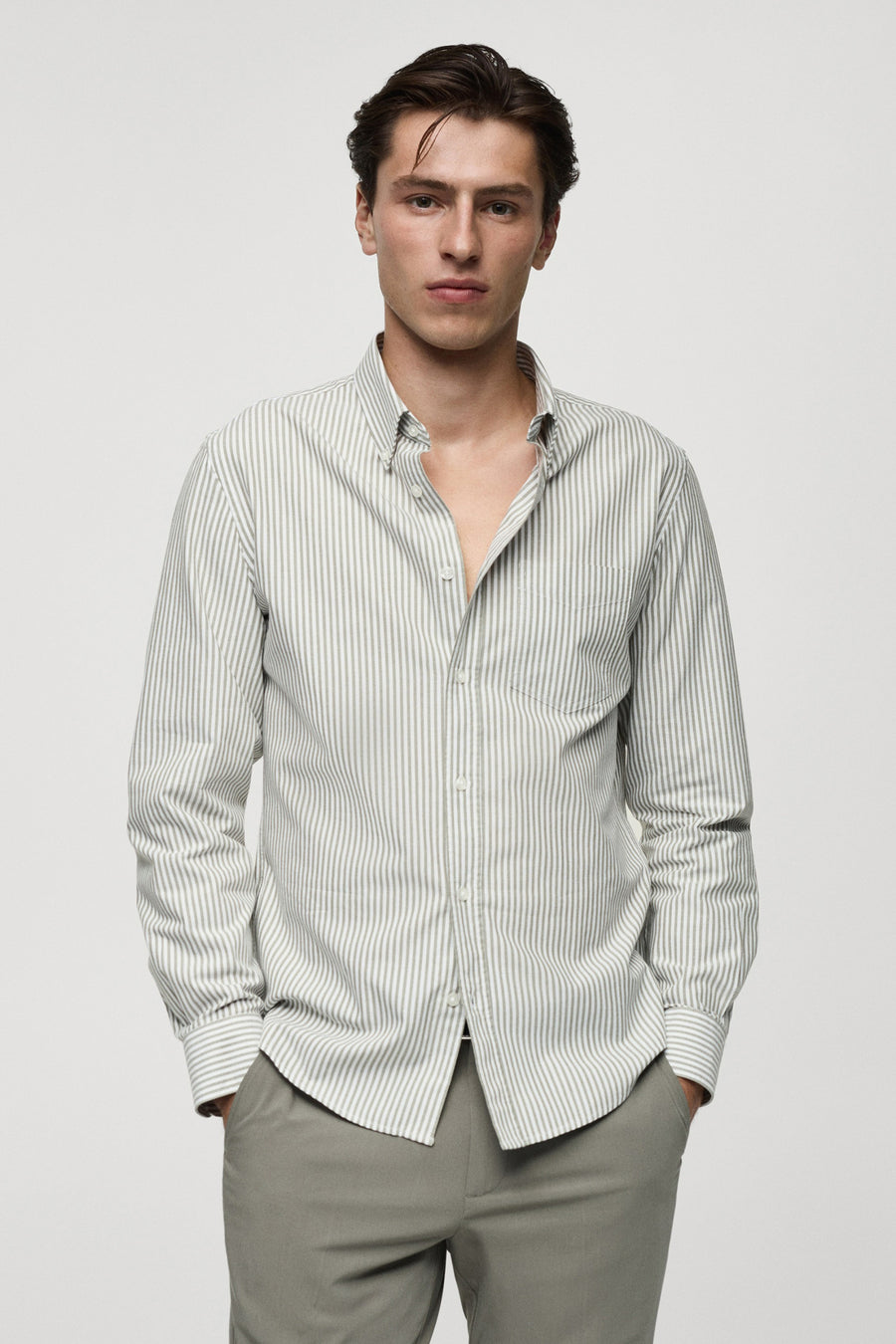 Chemise verte à manches longues de MANGO, rayée, dos nu, associée à un pantalon gris.