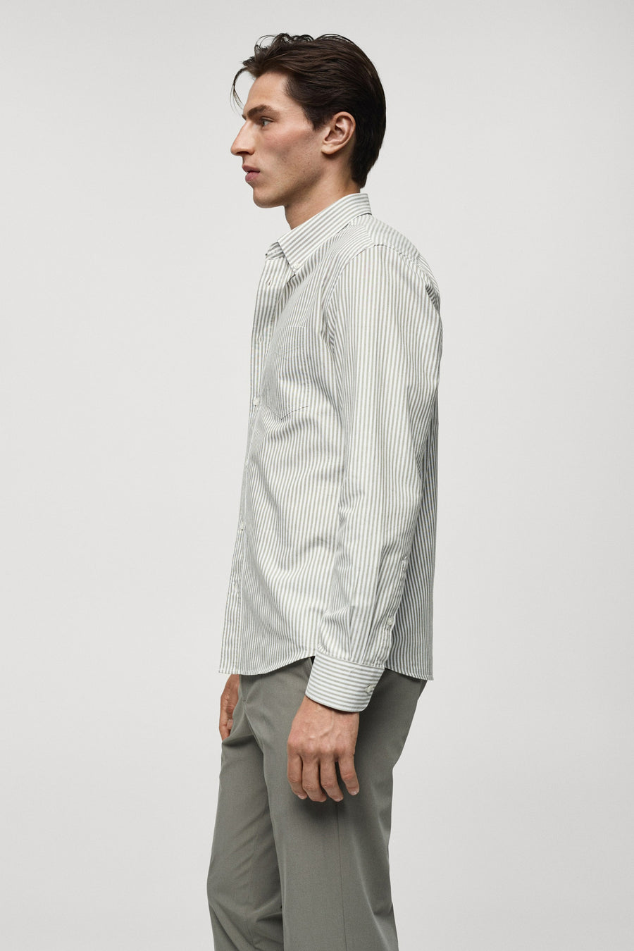 Chemise rayée verte avec longues manches de MANGO, montrée en profil latéral avec un pantalon gris.