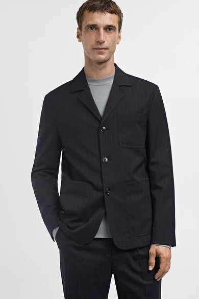 Blauwe blazer van MANGO met krijtstreep, gedragen over een grijze trui en bijpassende broek.