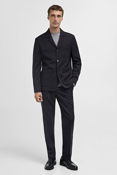 Blauwe blazer van MANGO, met subtiele strepen en een nonchalante grijze trui eronder.
