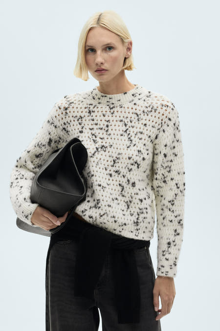 T-shirt blanc à col rond de MANGO, avec un motif à pois noirs, associé à une pantalon noir et une sac noir.