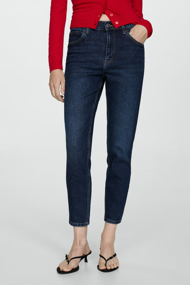 Donkerblauwe mom jeans van MANGO, gecombineerd met rode cardigan en zwarte slippers.