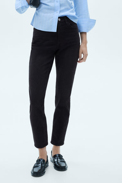 Zwarte mom jeans van MANGO, gecombineerd met een lichtblauw gestreept overhemd en zwarte instappers.