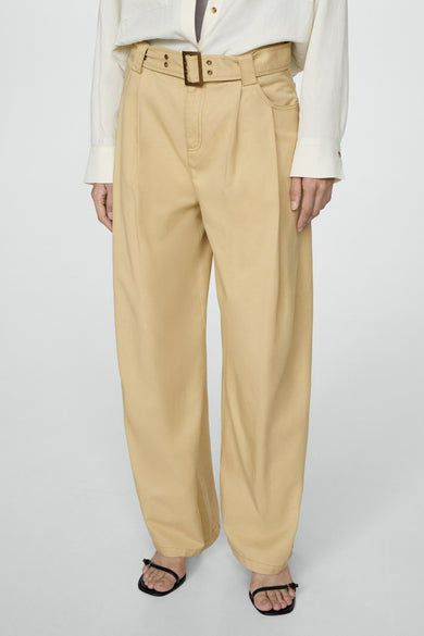 Pantalon beige de MANGO, avec une ceinture en tissu et une boucle bronzée, associé à un haut rayé et une blouse crème.