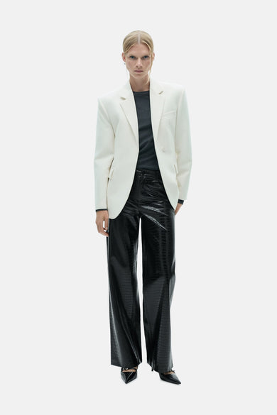 Pantalon noir à motif crocodile de MANGO, associé à un blazer crème et des escarpins noirs.