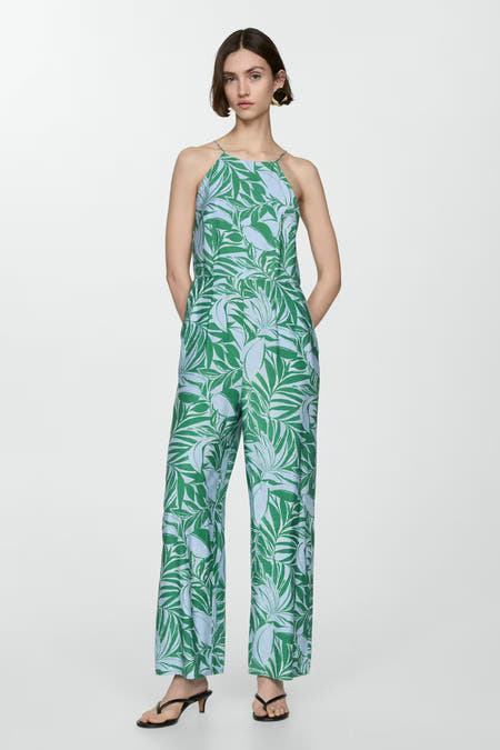 Blauwe jumpsuit van MANGO met groene bladprint, halternek en sandalen met hak.
